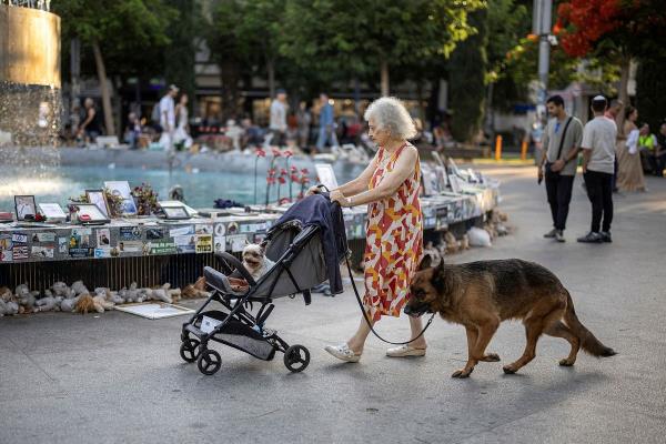 A woman walks past a fountain covered with memorabilia and pictures of hostages kidnapped during the deadly October 7 attack on Israel by Hamas, amid the o<em></em>ngoing Israel-Hamas conflict, at Dizengoff Square in Tel Aviv, Israel, June 13, 2024.